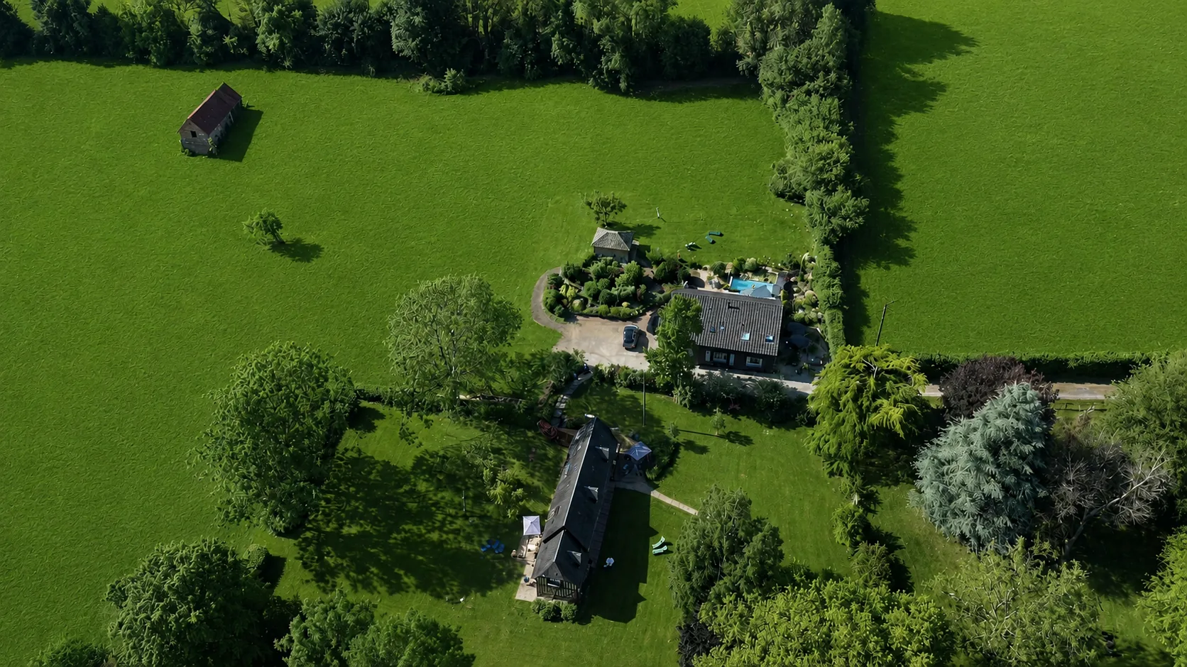 Le Hameau des Prés-Verts vu du ciel : ses maisons, la piscine et le jardin, entre les haies et les prés