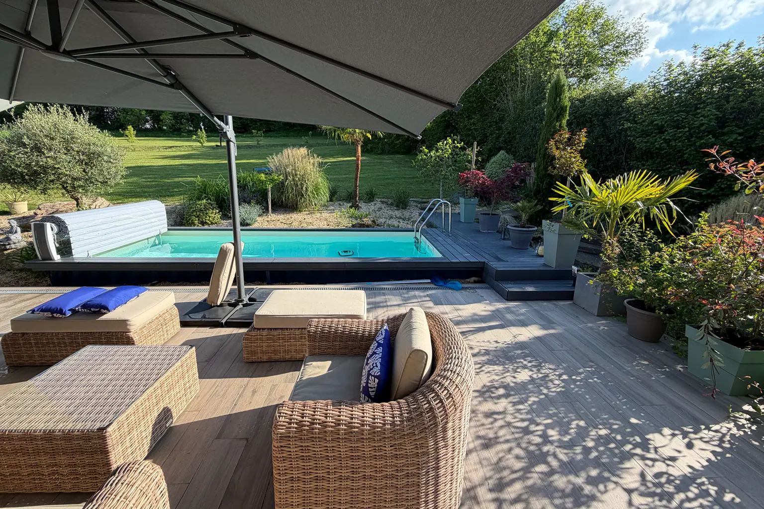 La piscine et sa terrasse de bois, le salon de jardin sous le parasol